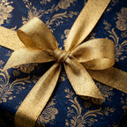 Close-up of a gift wrapped in elegant blue floral wrapping paper with a gold bow.