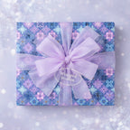 Blue snowflake Christmas wrapping paper with a sheer lavender ribbon and bow.