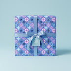 Square gift wrapped in floral wrapping paper with a blue satin ribbon and bow.