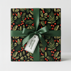 Elegant Christmas gift wrap featuring a black background with red berries and green pine branches, tied with a dark green satin ribbon.