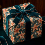 Celestial star Christmas wrapping paper with a teal velvet bow on a luxury gift box by Wrapped Studios.