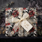 Elegant floral wrapping paper with deep red flowers, gold ribbon, and "With Love" tag. Wrapped Studios.