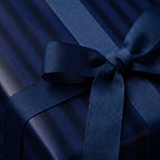 Elegant navy blue gift wrap with a striped pattern and matching ribbon bow.