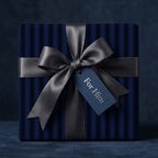 Navy gift wrapping with a grey ribbon and 'For Him' tag on a dark background