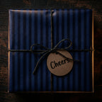 Dark blue striped gift wrap with "Cheers" tag and twine ribbon, perfect for celebratory occasions.