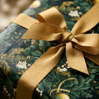 Elegant green floral wrapping paper with a gold ribbon bow on a holiday gift box, by Wrapped Studios.