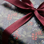 Close-up of a Wrapped Studios gift in floral Christmas wrapping paper with a burgundy ribbon.