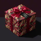 Elegant floral wrapping paper in red and gold with a satin ribbon bow. Wrapped Studios.