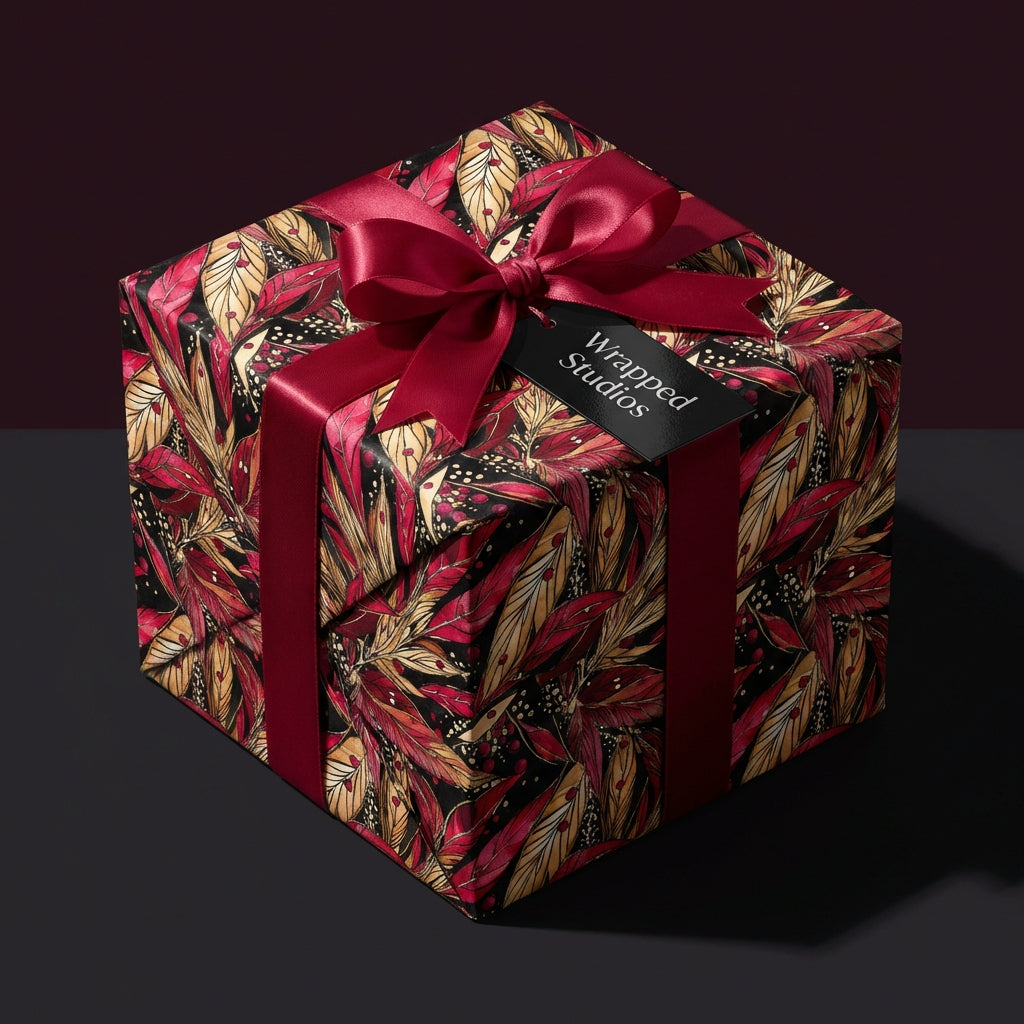 Elegant floral wrapping paper in red and gold with a satin ribbon bow. Wrapped Studios.