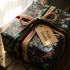 Christmas gift wrapped in dark floral paper with red berries, velvet ribbon, and "From Santa" tag.