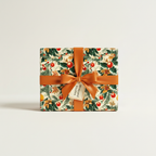Square gift box wrapped in vintage Christmas floral wrapping paper with an orange satin ribbon and bow.