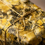 Elegant floral wrapping paper in gold hues, tied with a gold string bow.