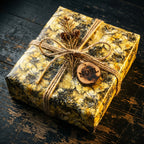 Rustic "Noel" Christmas gift wrap with gold floral pattern and twine bow by Wrapped Studios.