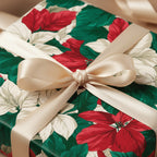 Festive Christmas gift wrap with red poinsettia floral pattern and gold ribbon bow.