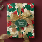 Elegant Christmas gift wrapped in floral poinsettia paper with a gold ribbon and "Warmest Wishes" tag.