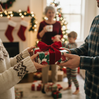 Christmas gift exchange featuring floral wrapping paper, a red velvet bow, and a happy family in the background.