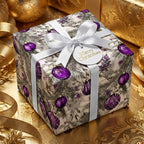 Elegant Christmas gift wrap featuring purple ornament pattern, tied with a white ribbon.