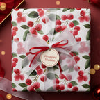 Elegant Christmas gift wrapped in floral berry wrapping paper with a sheer white ribbon and red accents.