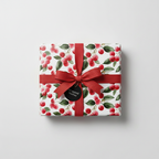 Square gift wrapped in festive floral wrapping paper with red berry design and a matching red ribbon.