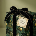 Luxury floral wrapping paper with a black velvet bow and a Wrapped Studios gift tag.