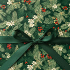 Dark green Christmas gift wrap with floral and berry pattern tied with a satin ribbon.
