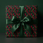 Elegant Christmas gift wrapped in red and green leaf print paper with a matching satin bow.
