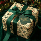 Wrapped Studios: Elegant Christmas gift wrap with green ribbon and a festive floral pattern.