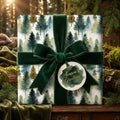 Elegant Christmas gift wrapped in watercolor forest tree paper with green velvet ribbon.