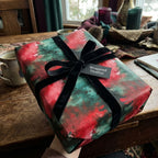 Wrapped Studios red and green Christmas gift wrap with black velvet ribbon bow.
