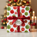 Festive Christmas wrapping paper with red and green ornament pattern, tied with a red satin ribbon and "Happy Holidays" tag.