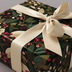 Elegant Christmas gift box wrapped in dark floral wrapping paper with ivory ribbon.
