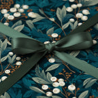 Elegant floral wrapping paper in teal and cream with a satin green ribbon tied in a bow.