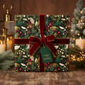Elegant Christmas gift wrapped in dark green floral wrapping paper with a velvet burgundy ribbon and "Happy Holidays!" tag.