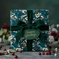 Elegant Christmas gift wrapped in navy floral paper with a velvet green ribbon and "Seasons Greetings" tag.
