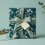 Elegant gift box wrapped in dark teal floral wrapping paper with a sheer sage ribbon.