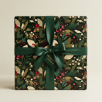 Elegant Christmas gift wrap: botanical floral pattern with deep green ribbon on a square present.