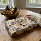 Kraft paper Christmas gift wrap from Wrapped Studios, featuring holly berries and a twine bow.