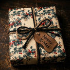 Christmas gift wrapped in vintage-style floral paper with twine and a "Merry X-Mas" tag.