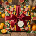 Square gift box in colorful floral & citrus fruit wrapping paper with red satin ribbon, Fresh Picked tag.