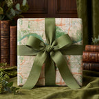 Vintage map wrapping paper with a sage green bow on a gift box, luxury gift wrap by Wrapped Studios.