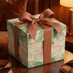 Luxury vintage map wrapping paper on a gift box with a large brown ribbon bow, by Wrapped Studios.