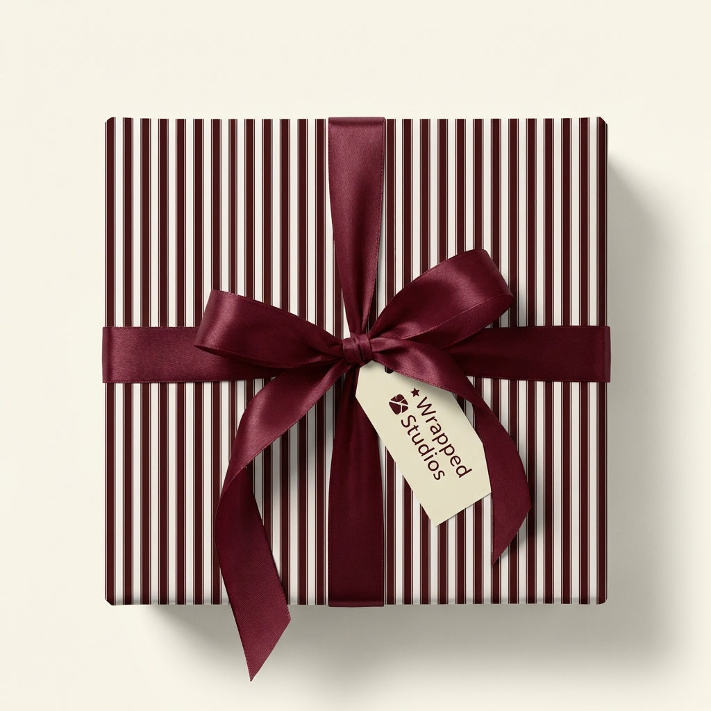 Burgundy striped wrapping paper on a square gift box with a satin bow.