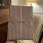 Striped gift box wrapped in brown and white paper with rustic twine bow.