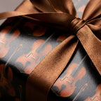 Violin music wrapping paper with a brown satin ribbon on a luxury gift box by Wrapped Studios.
