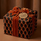 Elegant violin wrapping paper with a rust orange velvet ribbon and Wrapped Studios gift tag.