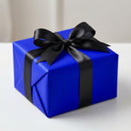 Elegant gift wrapped in royal blue wrapping paper with a black satin ribbon and bow.