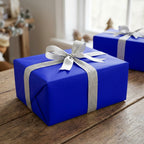 Royal blue wrapping paper with silver ribbon on a wrapped gift box.