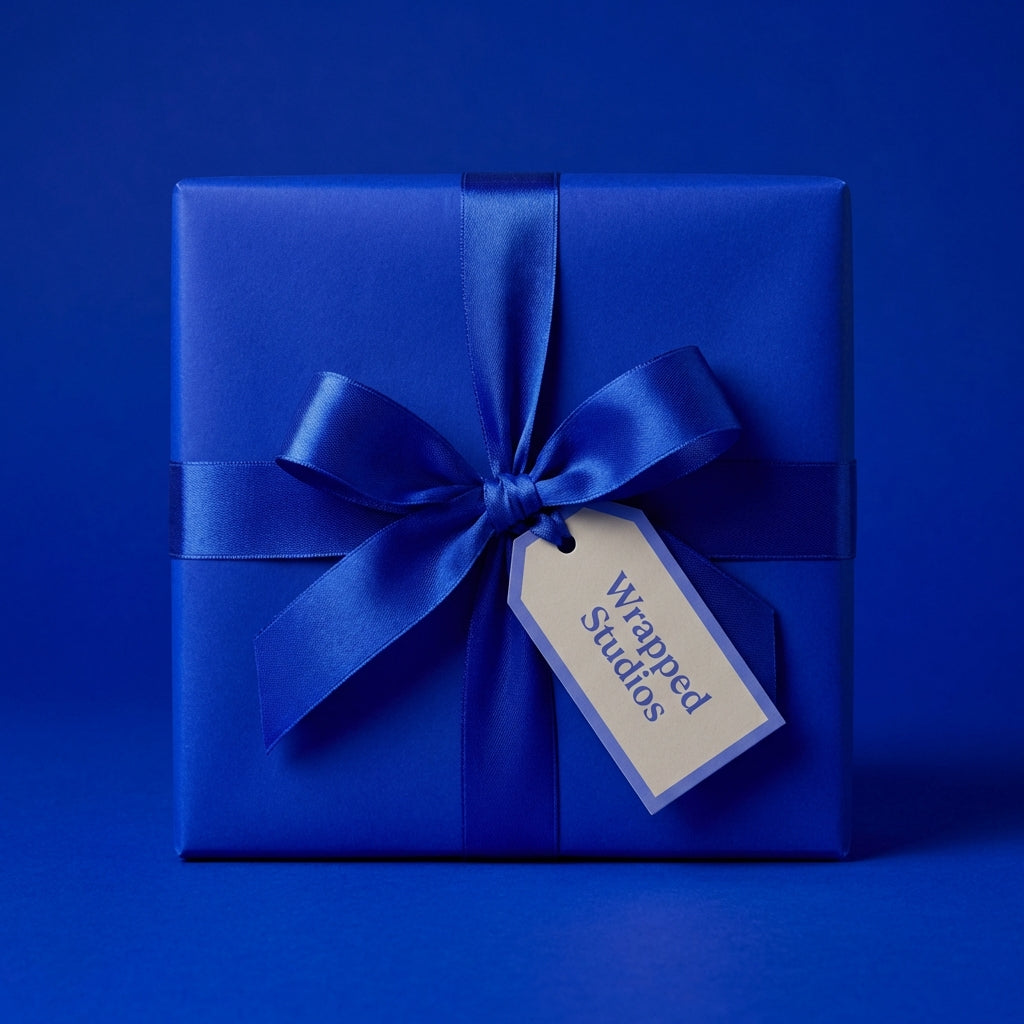 Royal blue gift wrapped in solid color paper with satin ribbon and bow for birthday, Christmas, or any occasion.
