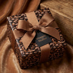 Coffee bean wrapping paper on a square gift box with a brown ribbon and bow.