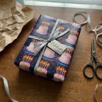 Birthday wrapping paper featuring cake and candles, tied with a silver ribbon and "Celebrate" tag.